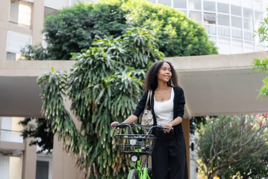 The woman stands beside her bicycle, appreciating her urban surroundings and promoting a sustainable lifestyle through cycling in a community environment.