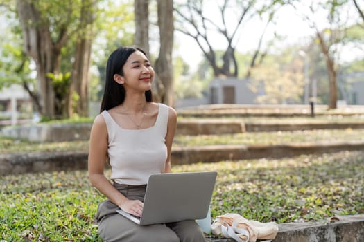 A young woman sits in a park with her laptop, embracing a sustainable lifestyle and enjoying the fresh air while working.