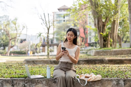 A young woman engages with her smartphone, embodying a sustainable lifestyle in a natural setting, showcasing modern connectivity.