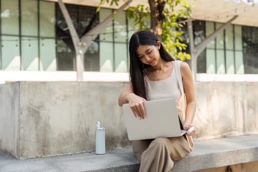 A young woman engages in sustainable habits, working on her laptop in an outdoor space, showcasing a blend of productivity and eco-friendliness.