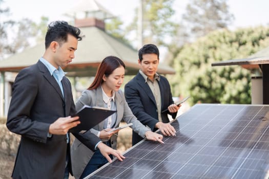Three business professionals, including two men and one woman, engaging in discussions about the features of solar panels, emphasizing teamwork and commitment to sustainability.
