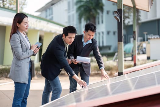 A diverse team of business professionals examining solar panels outdoors, showcasing teamwork and commitment to sustainable energy practices.
