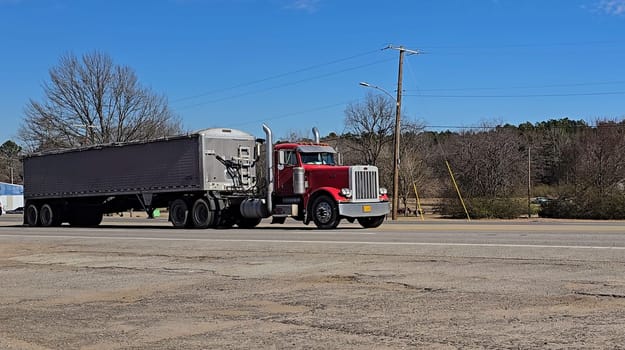Freight liner Semi-Truck Driving on Open Highway in a Rural Area, CDL Truck America, semi truck and trailer travels along an open road under a blue sky in a rustic rural setting, showcasing commercial transportation, logistics efficiency, and professional trucking