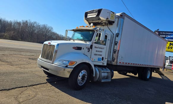 Freight liner Semi-Truck Driving on Open Highway in a Rural Area, CDL Truck America, semi truck and trailer travels along an open road under a blue sky in a rustic rural setting, showcasing commercial transportation, logistics efficiency, and professional trucking
