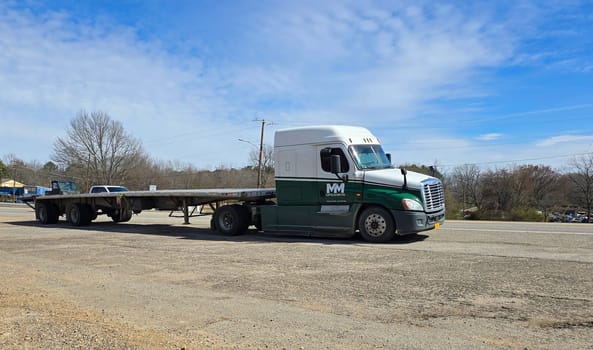 Freight liner Semi-Truck Driving on Open Highway in a Rural Area, CDL Truck America, semi truck and trailer travels along an open road under a blue sky in a rustic rural setting, showcasing commercial transportation, logistics efficiency, and professional trucking