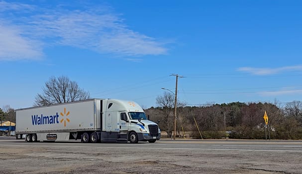 Freight liner Semi-Truck Driving on Open Highway in a Rural Area, CDL Truck America, semi truck and trailer travels along an open road under a blue sky in a rustic rural setting, showcasing commercial transportation, logistics efficiency, and professional trucking