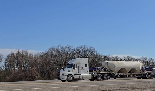 Freight liner Semi-Truck Driving on Open Highway in a Rural Area, CDL Truck America, semi truck and trailer travels along an open road under a blue sky in a rustic rural setting, showcasing commercial transportation, logistics efficiency, and professional trucking