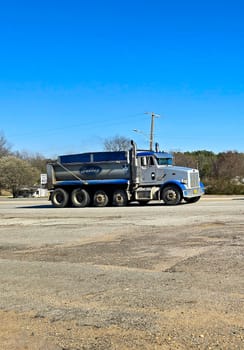 Freight liner Semi-Truck Driving on Open Highway in a Rural Area, CDL Truck America, semi truck and trailer travels along an open road under a blue sky in a rustic rural setting, showcasing commercial transportation, logistics efficiency, and professional trucking