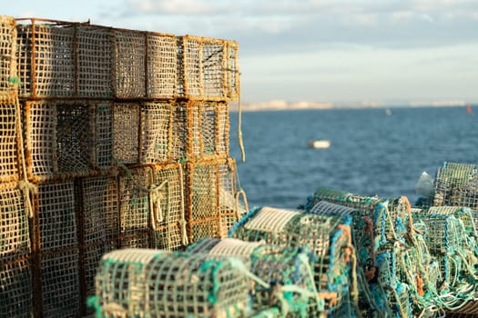 Stack of traditional lobster traps on coastal waterfront, used for capture fisheries and seafood collection, with ocean in background