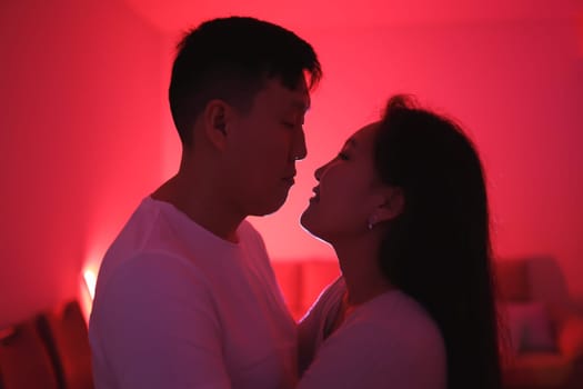 Romantic couple gazing at each other in a room bathed in red light