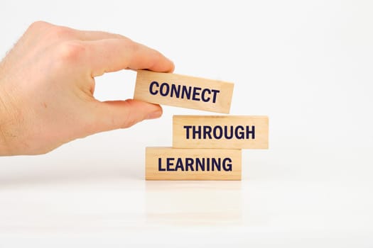 A hand arranges wooden blocks that spell connect through learning, emphasizing the importance of education and collaboration.