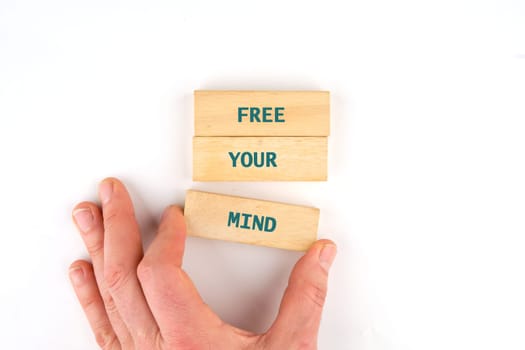 A hand positions wooden blocks that display the phrase Free Your Mind, emphasizing a theme of educational openness and creativity