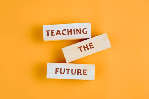 Wooden blocks display the phrase teaching the future against a bright yellow backdrop, symbolizing educational innovation and hope.