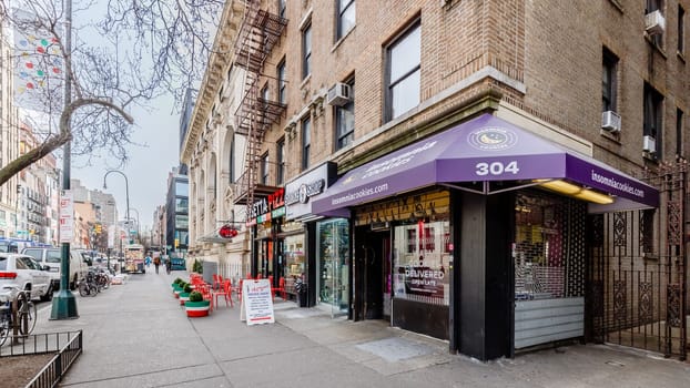 Manhattan, New York, USA - February 16, 2024: Street atmosphere and architecture of residential and commercial buildings on a gray winter day