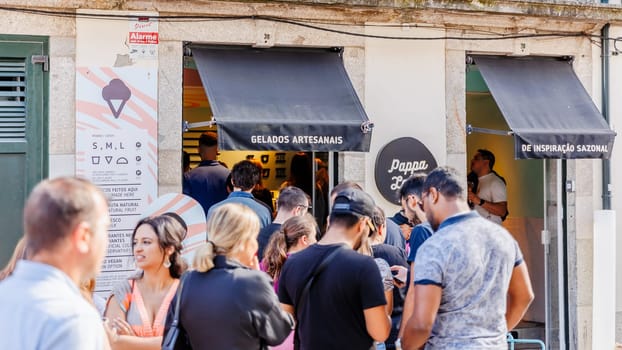 Braga, Portugal - May 26, 2024: Tourists queuing outside the famous artisanal ice cream parlor "Pappa Lab" in the historic city center on a beautiful spring day
