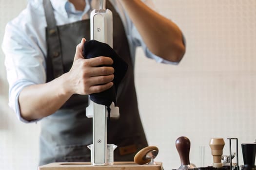 A meticulous barista cleans the coffee machine, ensuring high standards of cleanliness and hygiene in the preparation of sustainable coffee.