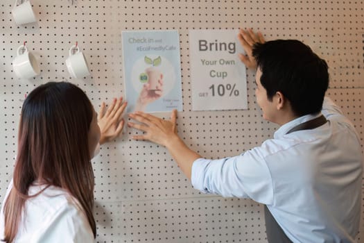 Two baristas actively engage with customers, showcasing a commitment to sustainability by advocating for the use of personal cups to reduce waste in a cozy cafe environment.