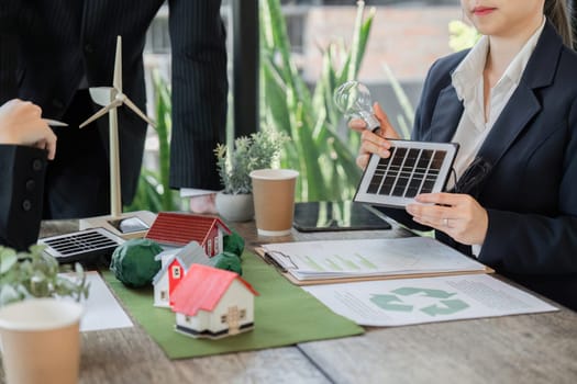 A team meeting focused on sustainability, where individuals explore renewable energy solutions using miniature models and data analysis.