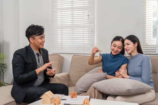 An insightful discussion as a real estate agent presents keys to two enthusiastic women, highlighting the success of their real estate deal.