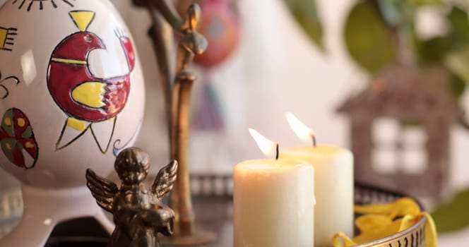 A vibrant display of handcrafted Easter decorations features colorful eggs and candles, with a charming angel figurine adding a serene touch to the festive setup. Perfect for celebrating Easter.