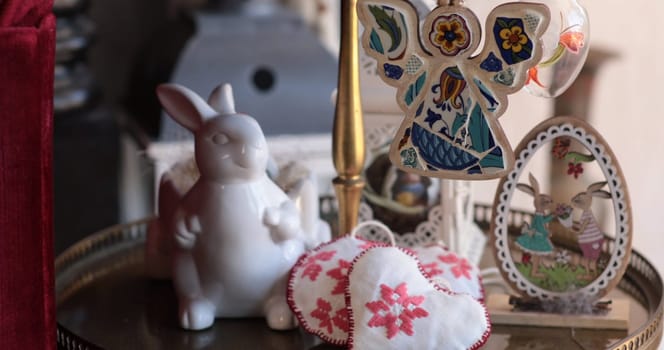 Handcrafted Easter decorations sit on a decorative table, featuring a white bunny, colorful ornaments, and stitched hearts, celebrating the joy of Easter.