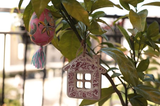 Handcrafted Easter decorations adorn a vibrant plant with a colorful Easter egg and a charming wooden house shaped ornament, creating a festive atmosphere perfect for the holiday.