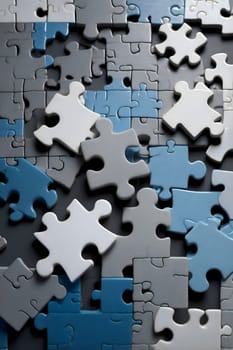 A variety of puzzle pieces in shades of blue, gray, and white lay scattered across a flat surface. The different shapes and colors form a visually engaging display, inviting interaction.