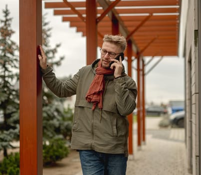 Young Attractive Man On A Street Makes A Stylish Portrait In A Scarf During A Phone Call