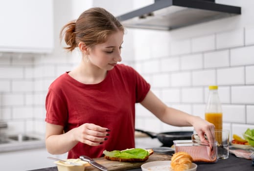 Young Girl Adds Ham To Sliced Croissant For Breakfast