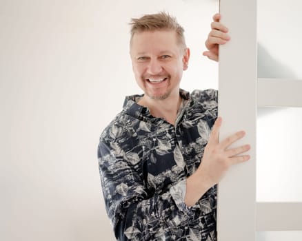 Happy Man Peeking Behind Door At Home