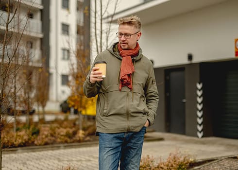 Young Attractive Man Stands On A Street Having Morning Coffee Near A Garage