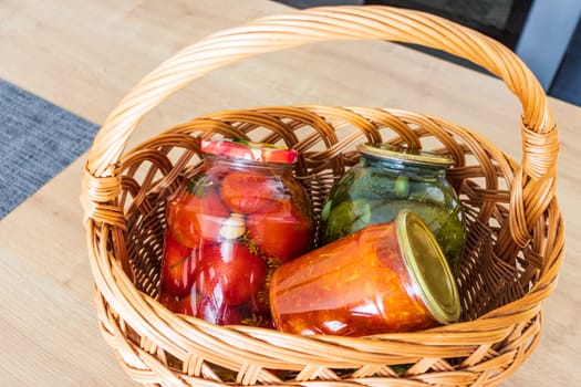 Jars with different types of pickles and preserves in a wicker basket