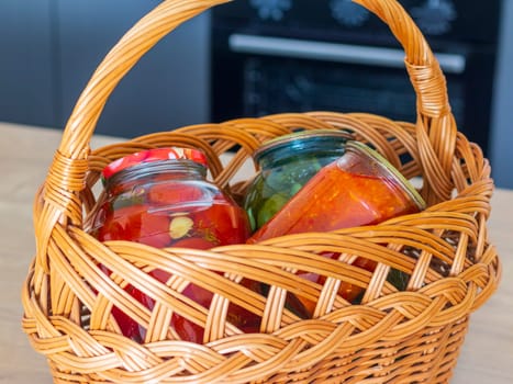 Jars with different types of pickles and preserves in a wicker basket. Food