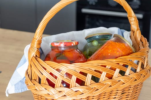 Jars with different types of pickles and preserves in a wicker basket. Food