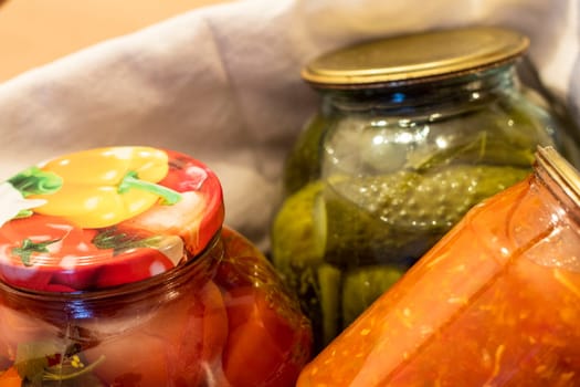 Jars with different types of pickles and preserves in a wicker basket. Food