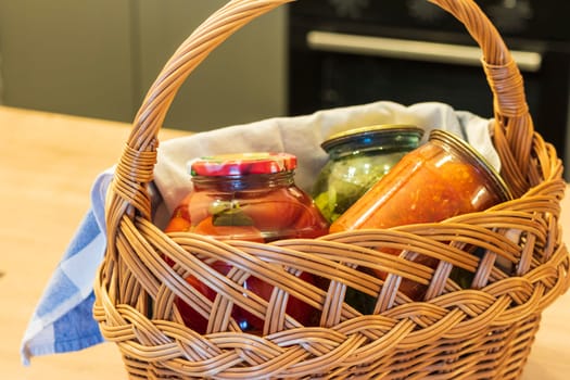 Jars with different types of pickles and preserves in a wicker basket. Food