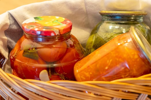 Jars with different types of pickles and preserves in a wicker basket. Food