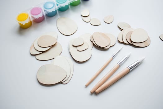 Art supplies with wooden egg shapes brushes and paints for creative projects.
