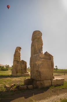 Twin statues of Colossi of Memnon, Luxor, Egypt. Hot air balloon overflying the theban necropolis