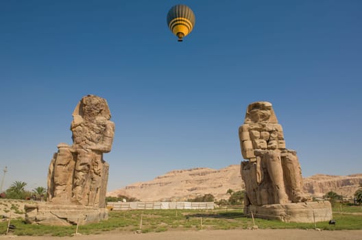 Twin statues of Colossi of Memnon, Luxor, Egypt. Hot air balloon overflying the theban necropolis