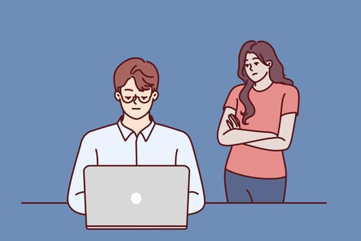 Frustrated woman near husband using laptop and suffering from internet addiction and working late into night. Concept of imbalance between internet career and family, causing resentment of loved ones