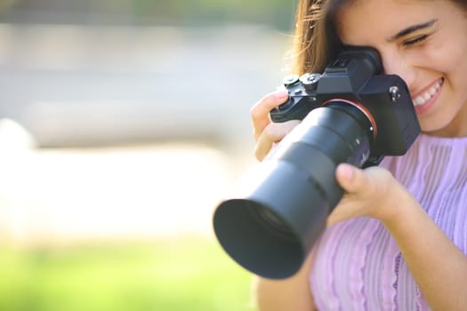 Happy photographer taking picture in a park with copy