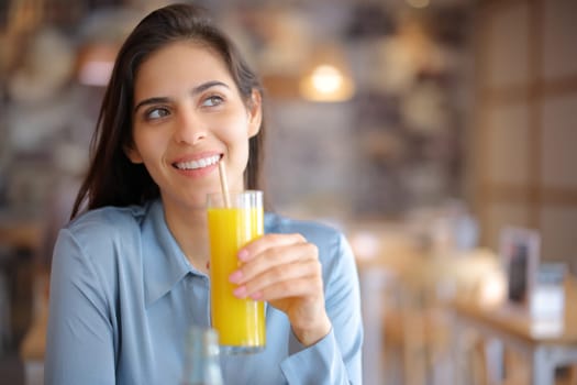 Happy pensive woman drinking orange juice in a bar looking at side