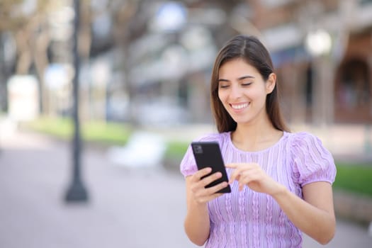 Happy person using cell phone walking in the street