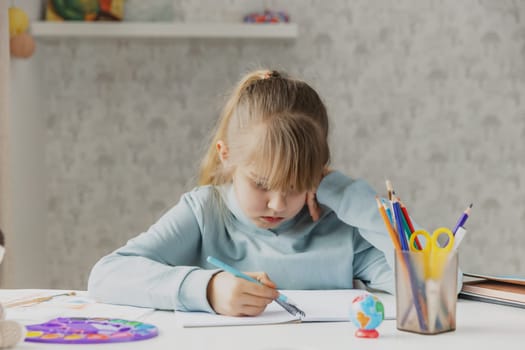 Exhausted schooler cute little girl sitting at desk, suffering from doing homework, tired from studying at home, stressed with difficult task, getting ready before exams. Home education, homeschooling