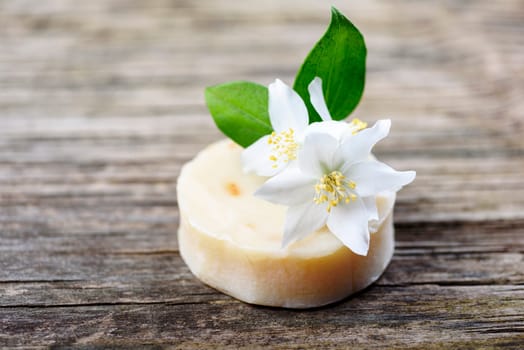 Closeup of organic handmade natural soap with goat milk and jasmine flower herbs on vintage wooden table. Skincare cosmetics. Spa, wellness, aromatherapy and bath product.