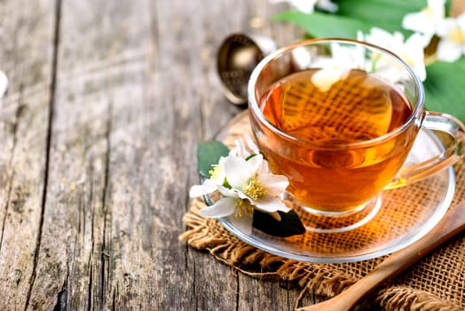 Herbal green tea border on wooden rustic background. Hot cup of jasmine tea on vintage textured table from above. Asian organic detox beverage. Alternative medicine food and drink concept.