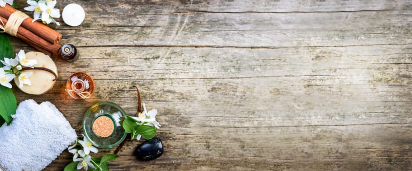 Top view of essential oils with jasmine, cinnamon and vanilla on rustic wooden table with copyspace. Spa and wellness aromatherapy treatment. Asian massage and skin care background design.