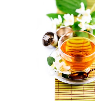 Herbal green tea with jasmine flower in transparent teacup border isolated on white background with cpyspace. Traditional asian hot beverage in glass cup. Organic healthy herbs for alternative medicine.