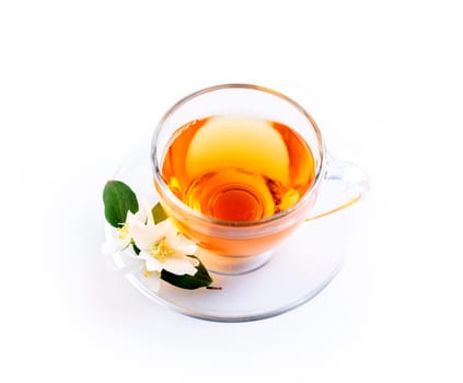 Asian green tea with jasmine flower in transparent teacup isolated on white background with reflection. Traditional chinese hot beverage in glass cup overhead. Organic healthy herbs for alternative medicine. Top view.